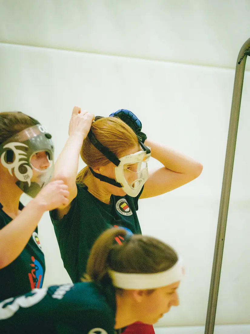 Eine Frau im schwarzen Trikot zieht sich eine durchsichtige Maske übers Gesicht