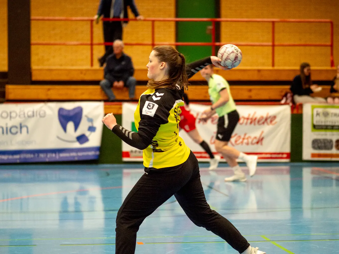 Eine Torfrau im gelben Trikot wirft den Ball aus dem Torraum ab.