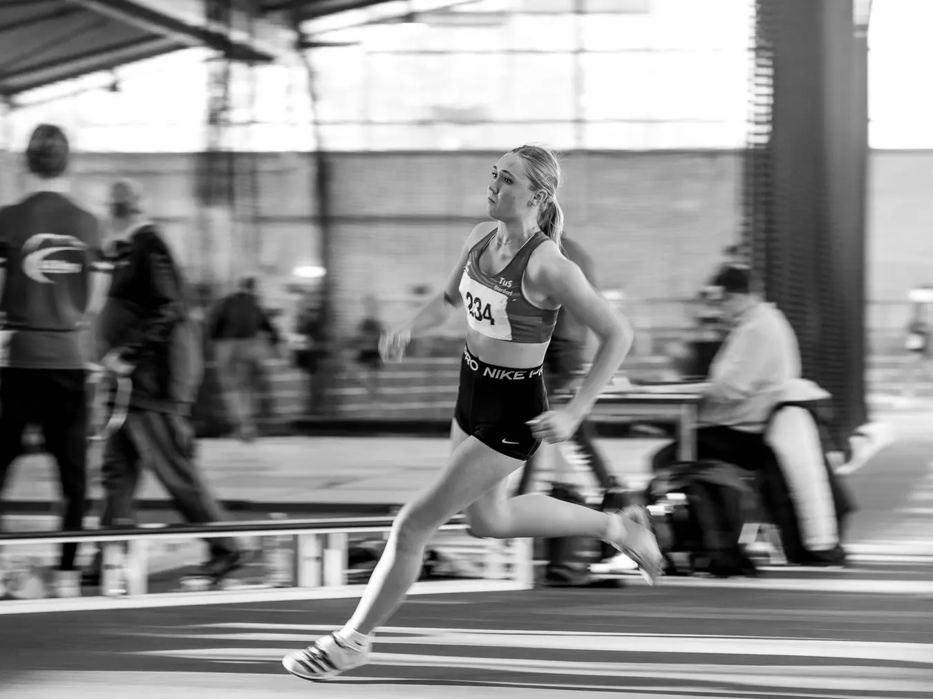 Eine Athletin läuft zum Hochsprung an, der Hintergrund ist in Bewegungsunschärfe verwischt.